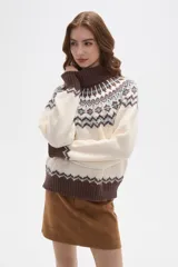 Sweater de punto con diseño jacquard en cuello, puños y ruedo. Presenta cuello alto, mangas largas y corte holgado.