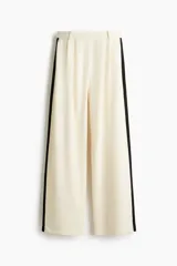 Pantalón sastrero de tiro alto y pierna recta, color blanco con franjas laterales negras. Cuenta con pinzas frontales y cintura elástica.