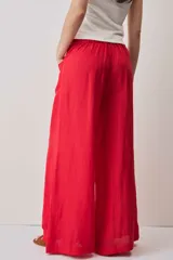 Pantalón rojo de corte ancho, estilo palazzo, tiro alto y bolsillos laterales.
