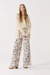 Cardigan color beige con lurex, escote en V, manga larga, botones de pasta, bolsillos delanteros y terminaciones de rib.