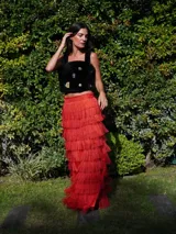 Falda larga de lino color naranja, con tajos laterales y volados de rafia. La cintura tiene elástico en la parte posterior.