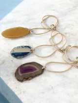 Collar con cordón de símil gamuza y dije de piedra ágata natural en forma irregular con terminaciones metálicas plateadas.