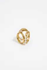 Anillo dorado con tres aros, uno con un cristal y otro con tres perlas.