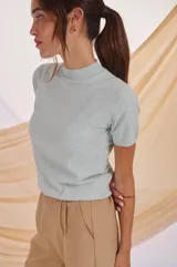 Polera de tejido de punto color celeste claro, de manga corta y cuello alto tipo mock neck.