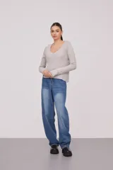 Sweater de tejido de punto fino, color beige, con escote en V profundo y mangas largas. Presenta un corte holgado y diseño minimalista.