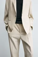 Pantalón de corte recto confeccionado en tejido con lana, color beige. Presenta bolsillos frontales, bolsillos traseros de vivo y cierre frontal con cremallera y botón.