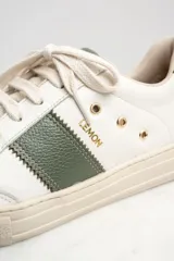 Zapatillas urbanas de cuero color blanco con detalles en verde.