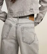 Pantalón de jean estilo baggy con corte holgado y recto, de tiro alto, con trabillas en la cintura, cierre tradicional y bolsillos laterales y traseros.