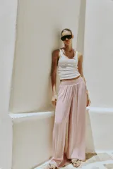 Pantalón fluido de tiro alto con cintura elástica y pernera ancha, de color rosado.
