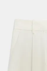 Pantalón cropped de tiro medio color blanco, perteneciente a la colección ZW Collection, con cintura con trabillas, bolsillos laterales ocultos, pinzas en el delantero, pierna ancha y cierre frontal con cremallera, botón y ganchos metálicos.