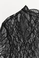 Top crop semitransparente de encaje negro, con cuello redondo y manga corta.