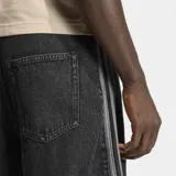 Short de jean negro con corte holgado, diseño de cinco bolsillos y las icónicas tres bandas de Adidas en los laterales. Presenta el logo del trébol bordado en la parte inferior.