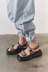 Sandalias de plataforma con suela de goma negra y tiras de cuero sintético color beige con cierre de velcro ajustable.