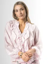 Camisa de organdí rosa pastel con finas rayas verticales metalizadas, escote en V con volados frontales y mangas largas abullonadas con puños elásticos.