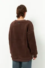 Buzo negro de tela tipo teddy, de manga larga y cuello redondo. Presenta recortes de nylon en mangas y laterales.