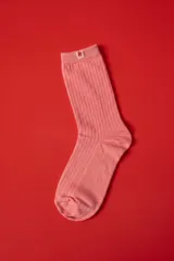 Medias de algodón acanaladas en color rosado, con etiqueta pequeña en el borde superior que presenta la letra R en color rojo.