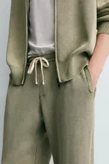 Pantalón relaxed fit tejido en hilatura de algodón con estructura, color verde militar. Presenta cintura elástica ajustable con cordón en contraste, bolsillos de vivo frontales y detalle de bolsillo trasero.