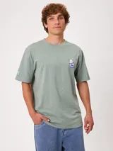 Remera Rusty de corte holgado, color amarillo, con estampa en la espalda de un personaje surfeando sobre un pez y textos descriptivos.