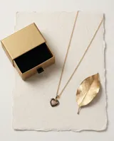 Collar de acero con baño de oro, compuesto por una cadena fina y un dije en forma de corazón que combina cerámica negra y circonias brillantes.