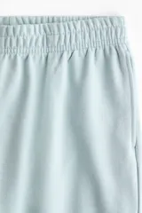 Pantalón deportivo de corte relajado y piernas rectas, confeccionado en felpa liviana de mezcla de algodón. Presenta cintura elástica fruncida y bolsillos laterales discretos.