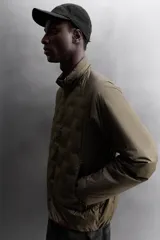 Cazadora deportiva acolchada color verde oscuro, con cuello alto y cierre frontal con cremallera. Cuenta con bolsillos laterales con cremallera oculta y un bolsillo interior.