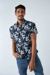 Camisa de manga corta con estampado botánico de hojas en tonos azul y blanco. Presenta cuello clásico, cierre frontal abotonado y corte slim.
