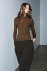 Jersey de punto con lana, de cuello subido y manga larga. Presenta un diseño ajustado con detalle de costuras verticales marcadas en el frente.