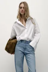 Jeans de tiro alto con diseño de cinco bolsillos, pernera recta y corte largo. Presenta cierre frontal con cremallera y botón metálico.