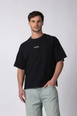 Remera de corte boxy y fit cuadrado, confeccionada en algodón grueso de alta calidad. Presenta un diseño minimalista en el frente con un pequeño logo circular y una estampa de gran tamaño en la espalda con la frase 'Designed in South America, Worldwide Clothes'.