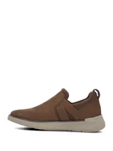 Zapatillas tipo slip on color marrón con inserciones elásticas laterales cruzadas y suela de goma en tono tostado.