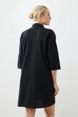 Túnica negra con bordados y bolsillos laterales.