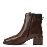 Bota de caña media confeccionada en cuero negro con acabado brillante. Presenta un taco cuadrado de altura media, puntera redondeada y detalle de hebilla metálica lateral con elástico para un mejor ajuste.