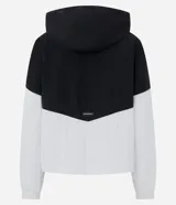 Campera rompeviento deportiva con diseño bicolor en negro y blanco. Presenta capucha con cordón ajustable, cierre frontal y puños elásticos.