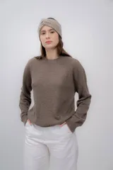 Vincha de lana color beige, tejida a mano, con diseño trenzado en el frente.
