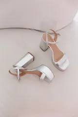 Sandalias plateadas con plataforma y tacón cuadrado. Tira delantera ancha y tira fina con hebilla al tobillo.