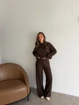 Conjunto de dos piezas compuesto por una remera de manga larga y un pantalón de corte recto, ambos confeccionados en tejido de punto texturizado color marrón.