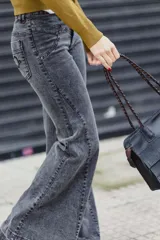 Jean de tiro medio con corte acampanado, confeccionado en denim gris oscuro con efecto lavado. Presenta costuras decorativas y detalles de bordado en la zona de la cintura y bolsillos.