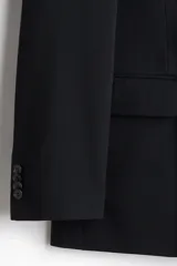 Blazer negro de doble botonadura con solapas de pico, bolsillo superior, bolsillos delanteros ribeteados con solapa, tres bolsillos interiores, botones decorativos en los puños y abertura doble atrás.