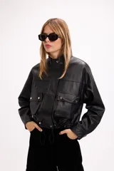 Campera corta de cuero sintético en color beige, con diseño de calce relajado, cierre frontal metálico, bolsillos con solapa en el frente y cordón ajustable en el ruedo.