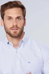 Camisa casual celeste de manga larga con diseño a rayas finas, cuello con botones y bolsillo ojal en el pecho con logo bordado.