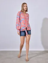 Blusa estampada con cuello a la base, escote en V y aplique de puntilla. Terminación de ruedo con nudo.