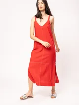 Vestido largo color crudo de lino, con silueta recta, escote en V, breteles anchos, detalle de elástico en la espalda y tajos laterales.