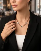 Collar de cadena de eslabones en acero con baño de oro rosa, que presenta tres dijes circulares con centro de ónix negro y bordes grabados con números romanos.