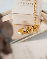 Pulsera dorada de eslabones gruesos con cierre tipo barra T y dije de corazón con incrustaciones brillantes.