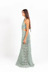 Vestido largo de encaje con patrón circular, color lila, de corte halter con tiras cruzadas al cuello y aberturas laterales en la cintura.