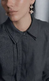 Camisa de lino con diseño de doble cuello, cartera oculta y tablas frontales que aportan movimiento. Presenta un corte clásico y elegante.