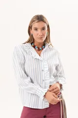 Camisa de manga larga con diseño a rayas celestes y blancas, cuello alto y detalle de volados en la cartera frontal y los puños.