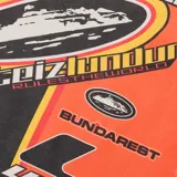 Buzo de manga larga Corteiz con diseño gráfico estilo motocross en colores naranja, negro y amarillo. Presenta múltiples estampados con logotipos y tipografías en el frente y las mangas.