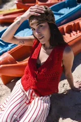 Chaleco corto tejido a mano en crochet, color celeste, con silueta ajustada, sin mangas y lazos en la delantera.