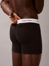 Pack de tres bóxers Calvin Klein tipo boxer brief de algodón elástico. Incluye un modelo negro con monograma estampado, uno azul oscuro liso y uno gris claro liso. Todos cuentan con cintura elástica blanca con el logo de la marca.